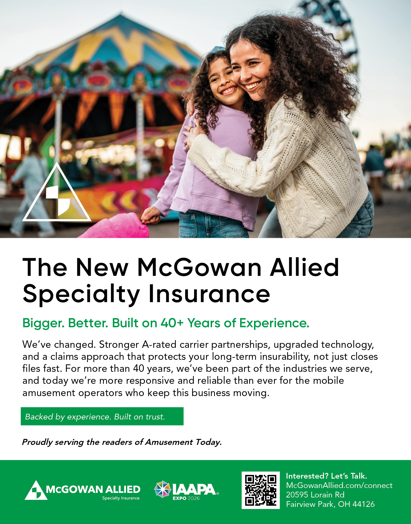 Two people with curly hair smile and hug each other in front of a colorful amusement park ride, accompanied by text promoting McGowan Allied Specialty Insurance for mobile amusement operators. Description generated by AI