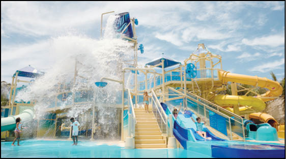 Children are playing and sliding on colorful water slides while a large bucket pours water down in a lively water park setting. Description generated by AI