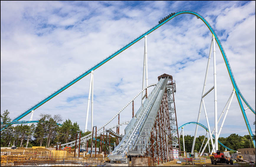 A roller coaster under construction with visible tracks, support beams, and construction equipment in an outdoor setting. Description generated by AI