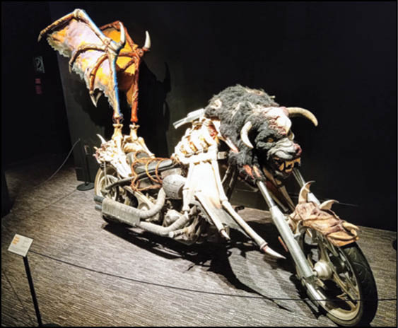 A custom motorcycle designed with a fantasy theme featuring dragon wings and a creature head integrated into the front. Description generated by AI