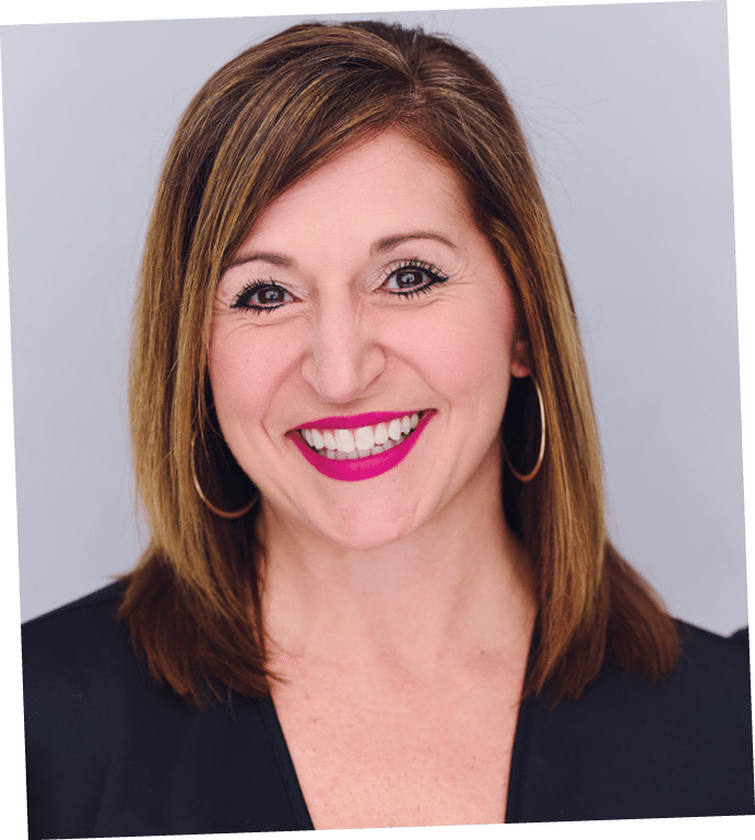 A person with shoulder-length straight hair wearing hoop earrings and a black top is smiling against a plain light background. Description generated by AI
